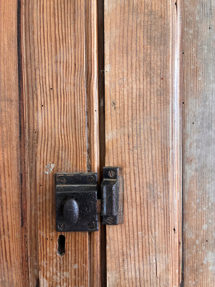 Close-up of the rustic latch on a tall rustic pine housekeepers cupboard, showcasing its vintage charm.