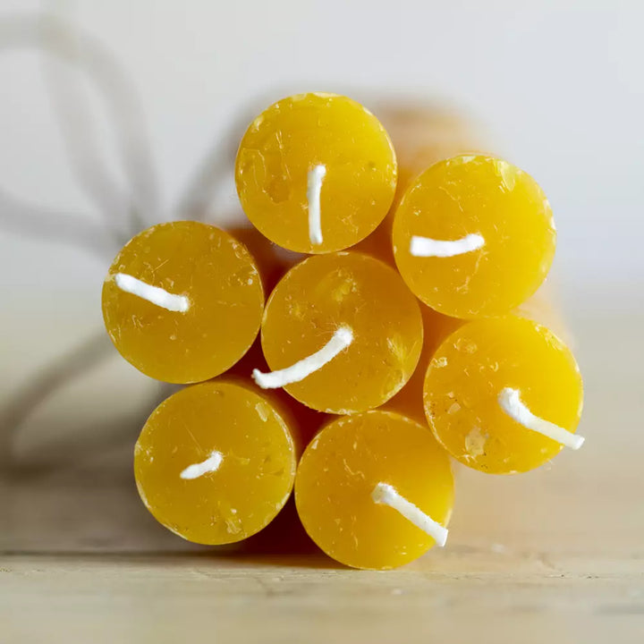 Set of Three Rustic Yellow Ochre Dinner Candles arranged with their wicks facing up on a light wooden surface.