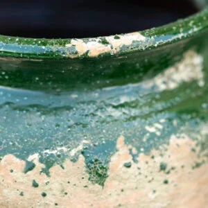Close-up of a rustic vase with green glaze and weathered texture, perfect for vintage home decor from Source for the Goose, Devon.