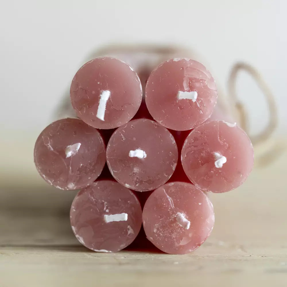 Set of Three Rustic Dusky Pink Dinner Candles stacked elegantly on a wooden surface, showcasing their soft, muted hue.