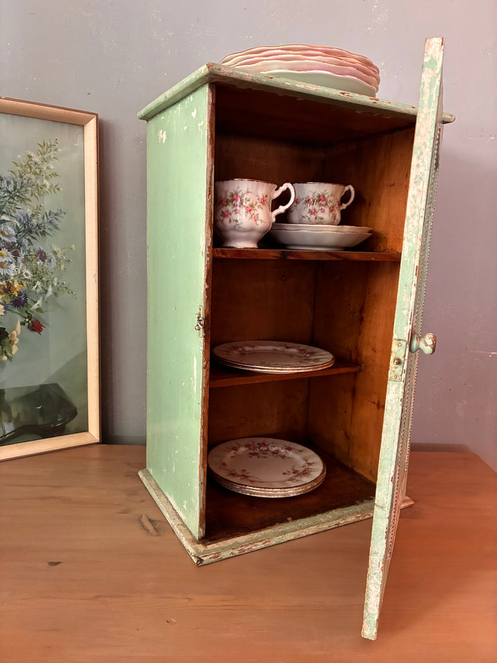Small Green Wooden Cabinet - vintage with decorative trim, showcasing antique appeal and filled with porcelain dishware.