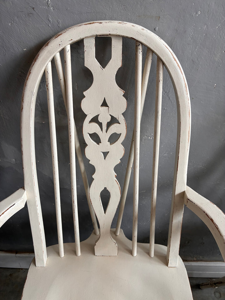 Set of Four Painted Wheelback Carver Chairs with carved wheel motif and distressed white finish.