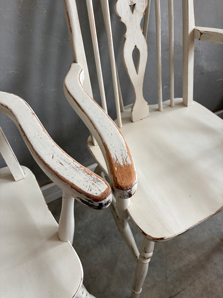 Set of Four Painted Wheelback Carver Chairs featuring a rustic design and distressed white finish.