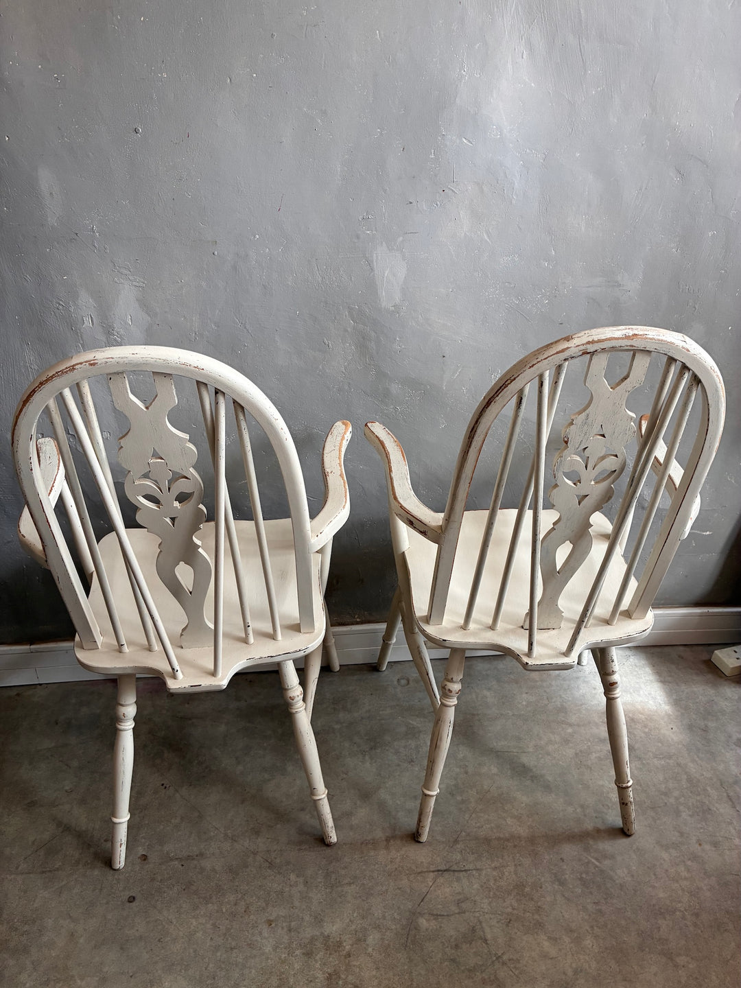 Set of Four Painted Wheelback Carver Chairs showcasing distinctive carved designs in warm white finish.