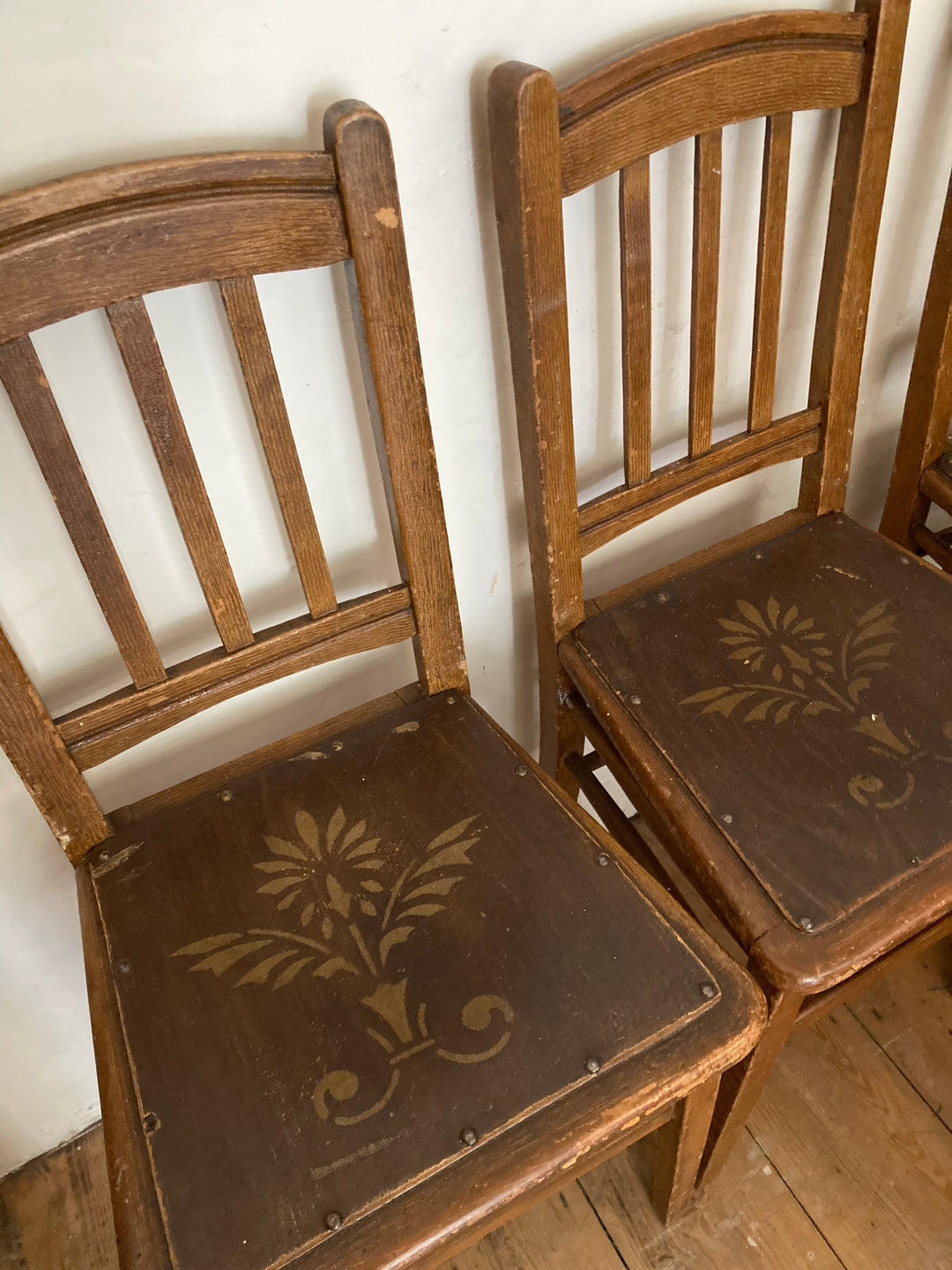 stencilled design on wooden seat on set of four vintage chairs