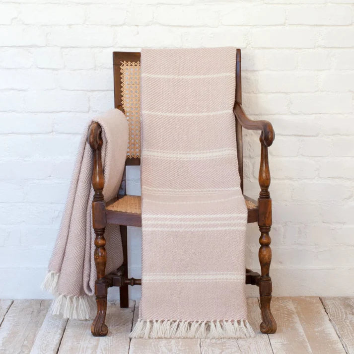 Weaver Green Oxford Stripe Blanket in Shell Pink placed on a chair alongside Herringbone Shell Pink