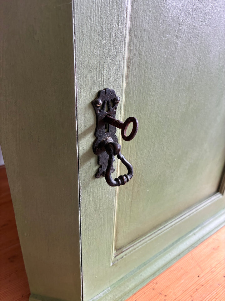 Close-up of the black metal escutcheon and key on a Small Vintage Green Painted Wall Cupboard from Source for the Goose, Devon.