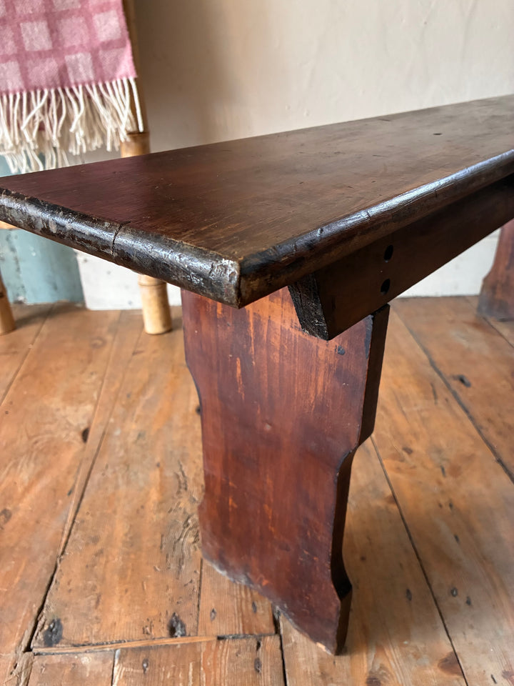 Close-up of a Small Antique Pine Bench showing its dark brown finish and sturdy legs, perfect for cozy spaces.