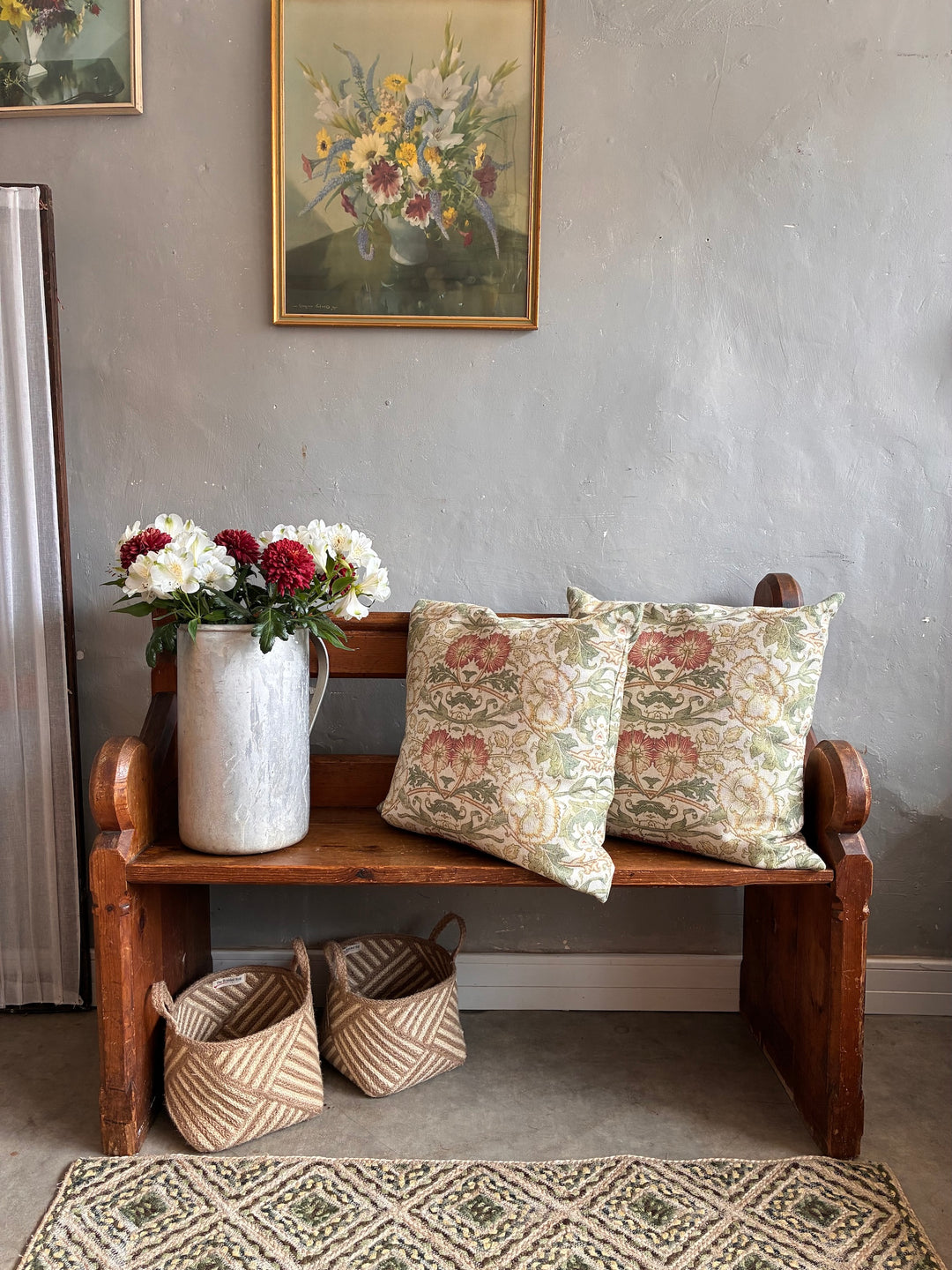 Vintage small antique church pew with decorative pillows, flowers, and baskets, adding rustic charm to a cozy home.