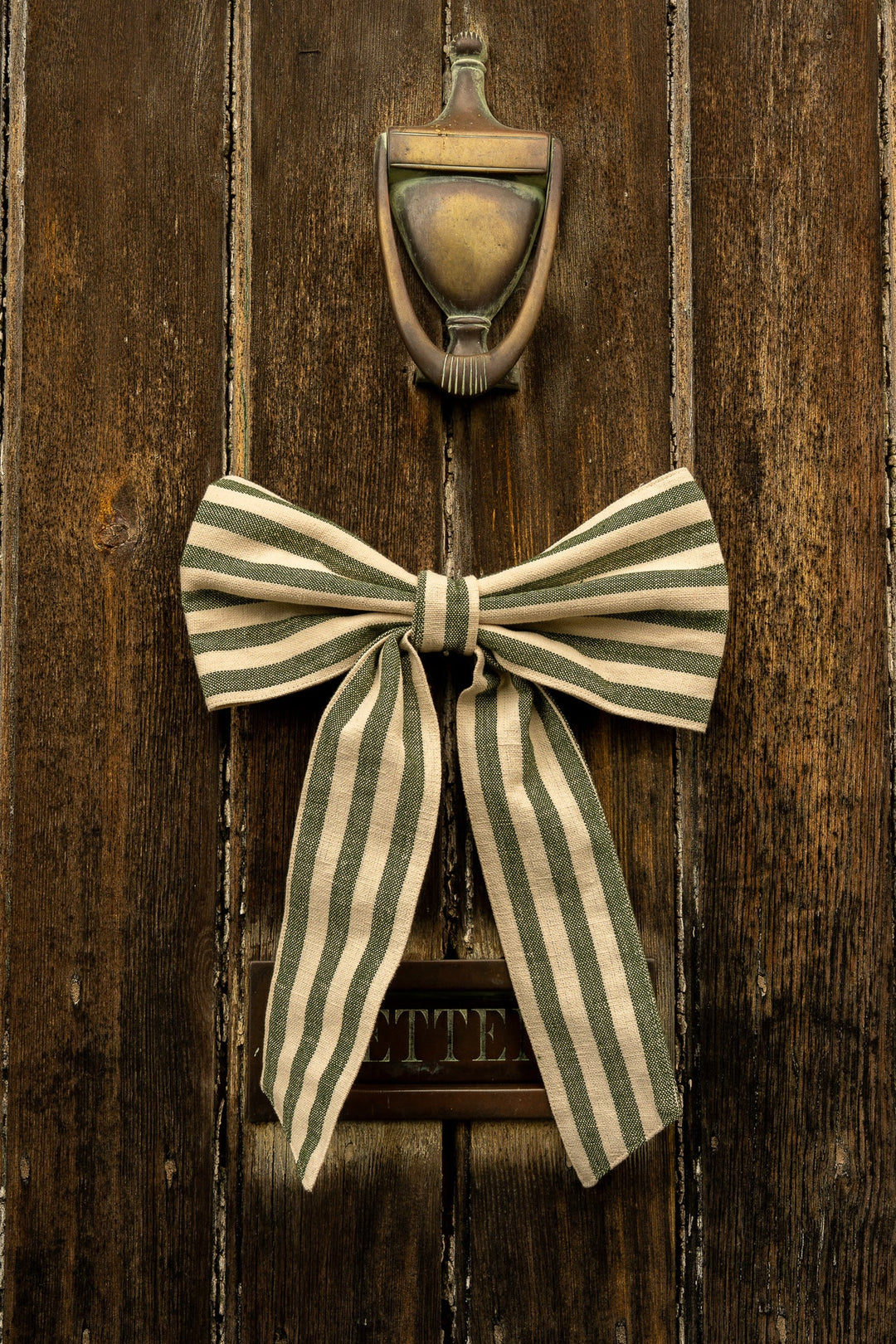 Small Ticking Stripe Bow - Pine Green hanging on a rustic wooden door, showcasing vintage style and cottage core charm.