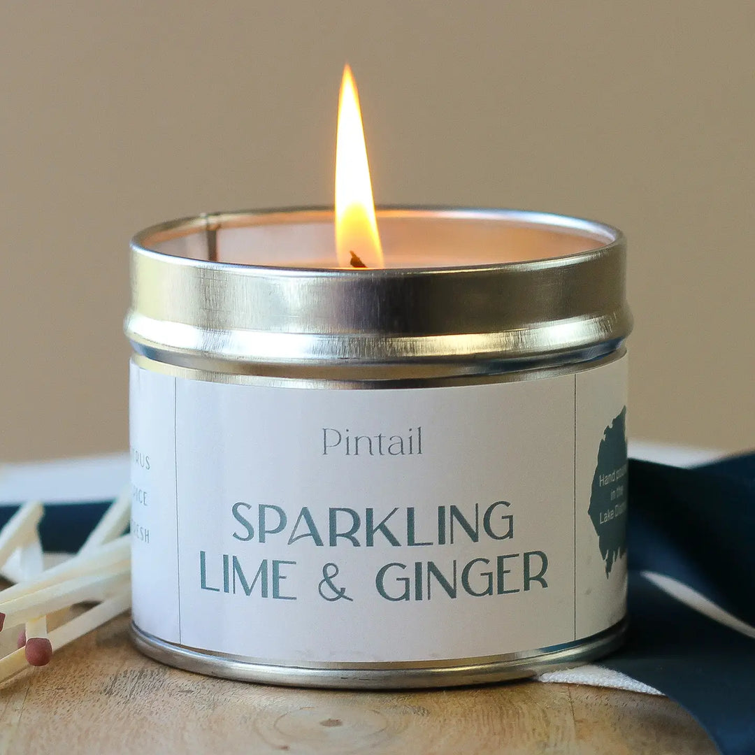 Pintail Candle - Sparkling Lime & Ginger Classic Tin with a glowing flame, showcasing its refreshing scent.