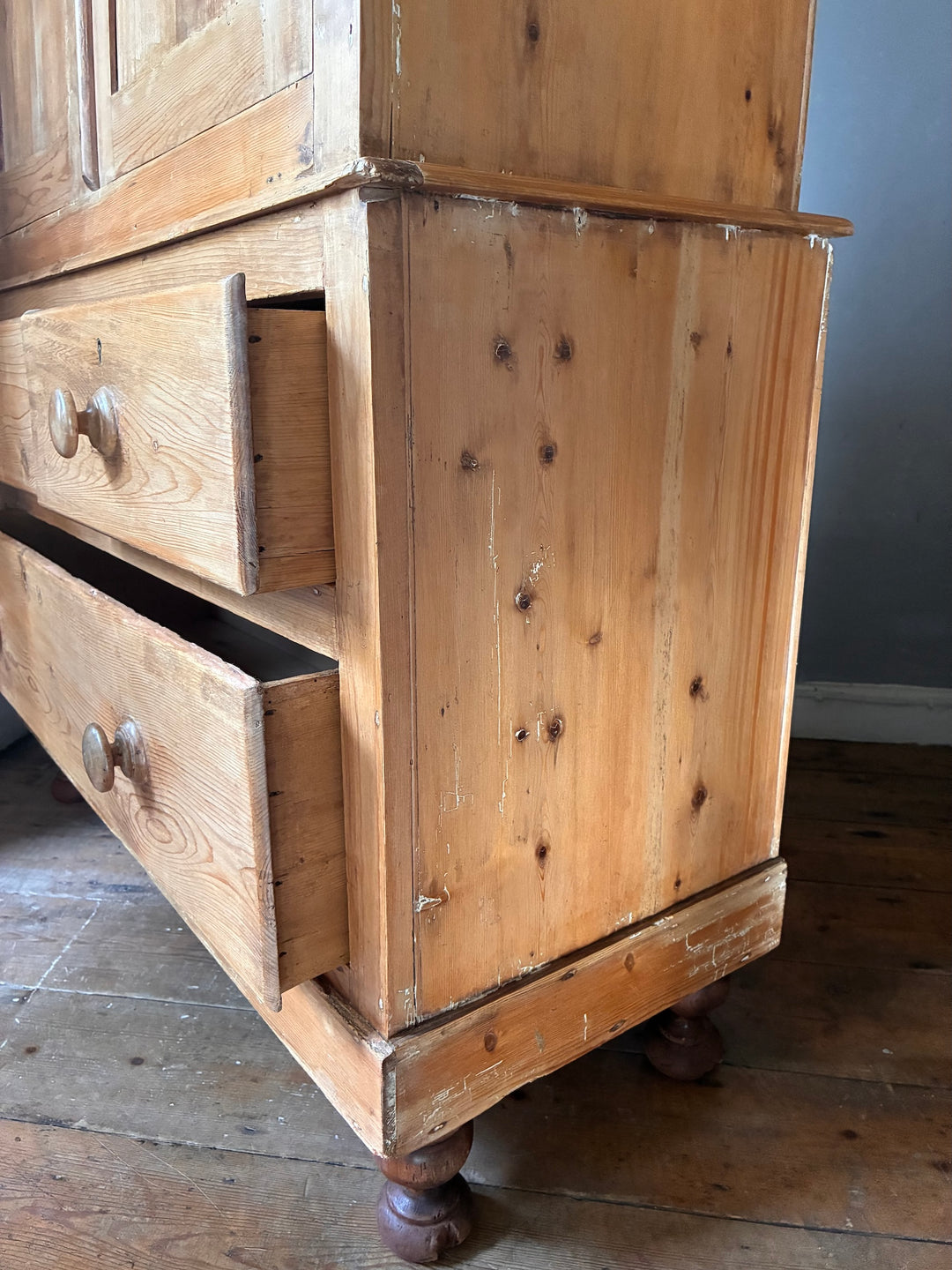 Close-up view of Victorian Stripped Pine Linen Cupboard showcasing its wooden drawers and turned feet.