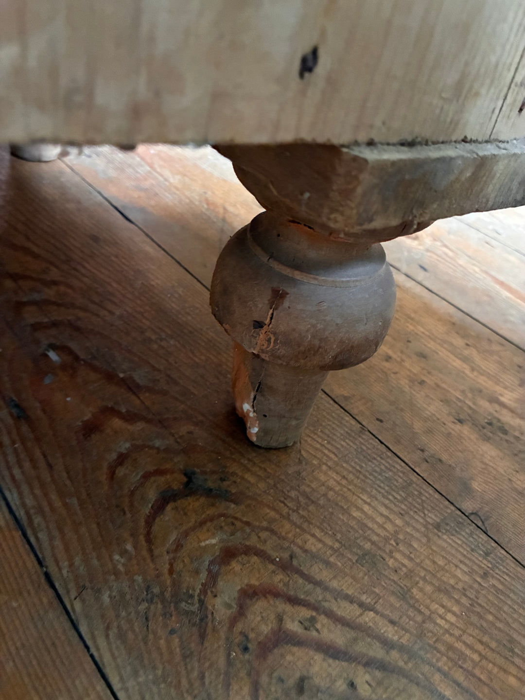 Leg detail of a Tall Rustic Antique Pine Chest of Drawers showcasing turned feet on wooden floor.