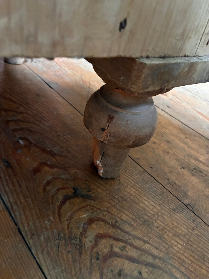 Leg detail of a Tall Rustic Antique Pine Chest of Drawers showcasing turned feet on wooden floor.