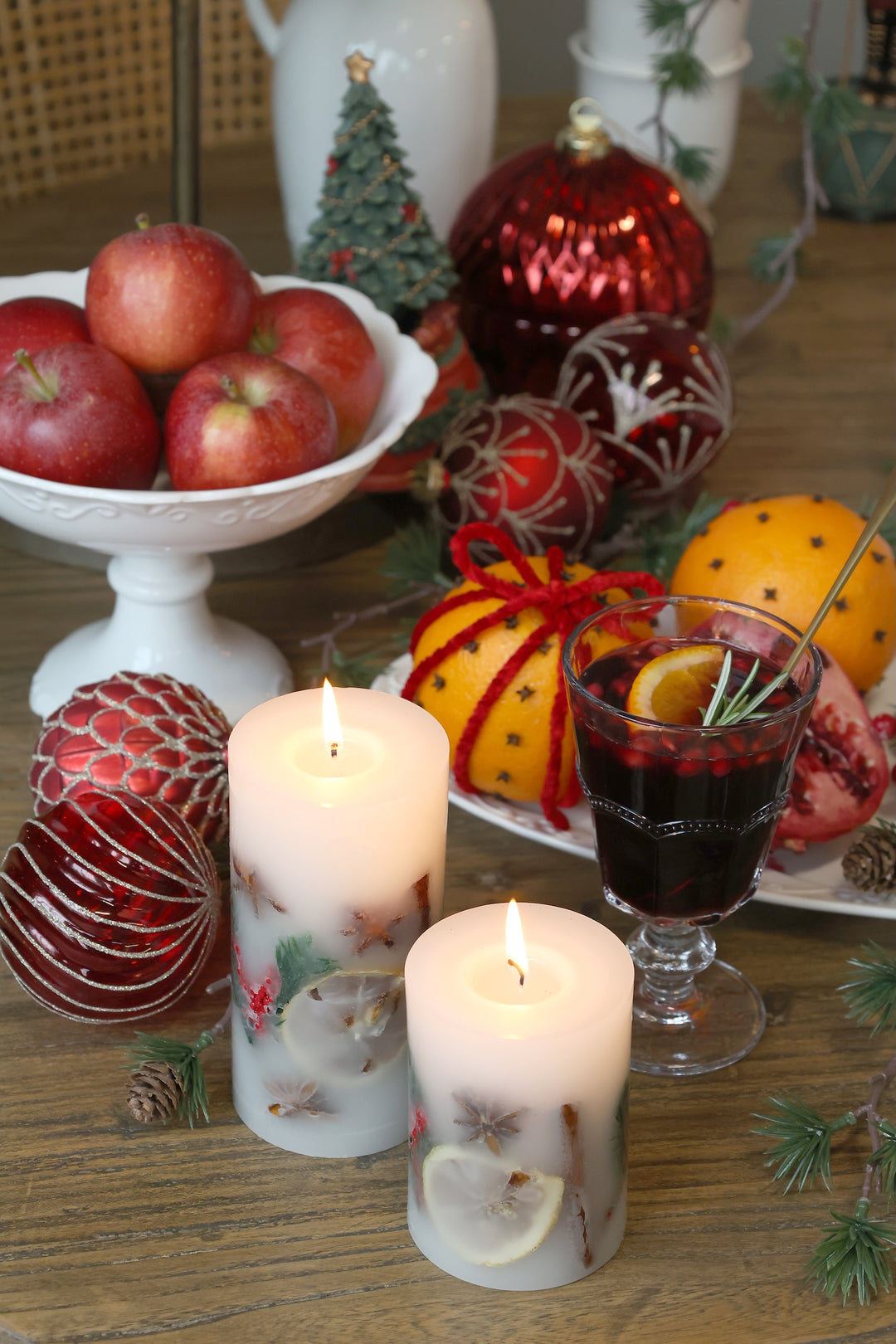 Christmas Spice Pillar Candles with festive decorations, apples, and holiday drinks on a rustic table setting.