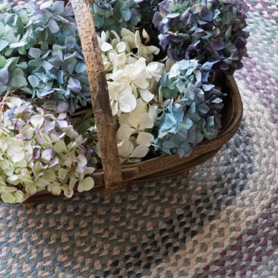 Basket filled with multicolored hydrangeas on a textured jute braided rug in Tundra