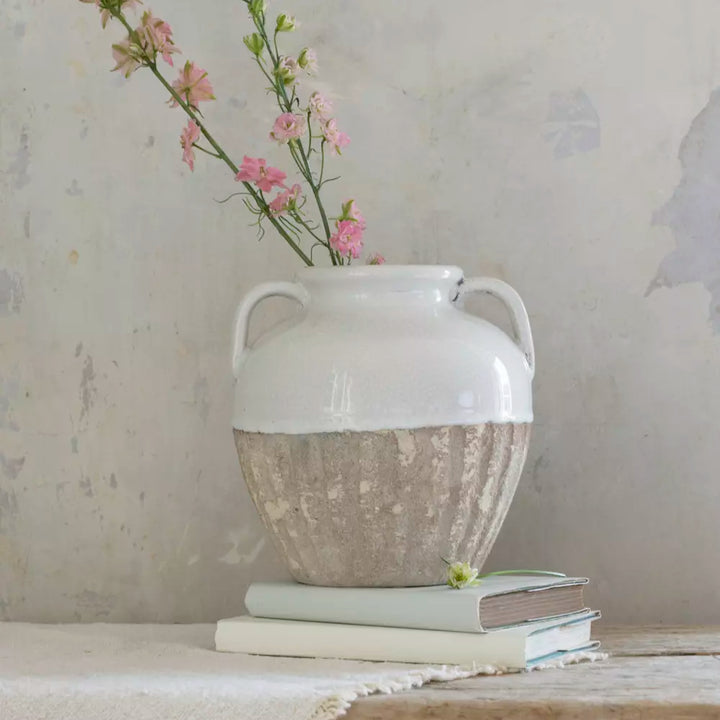 Small Antique White Amphora Vase with floral arrangement on stacked books.