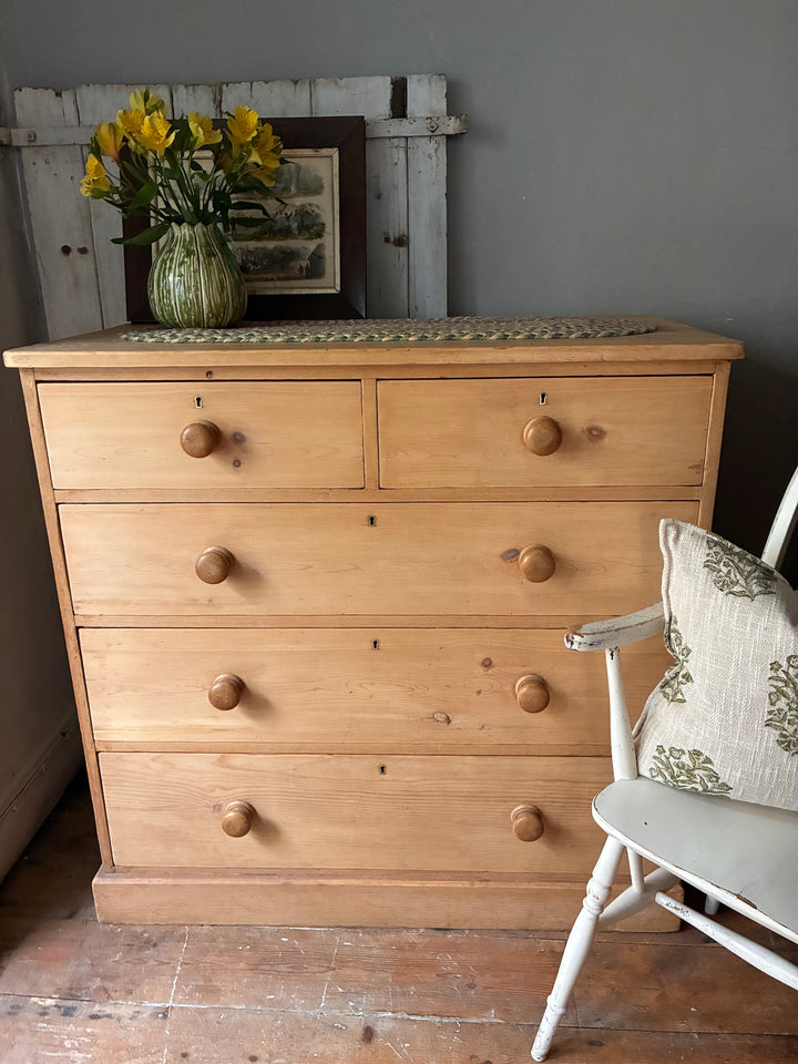 Victorian Antique Pine Chest of Drawers with floral arrangement on top and a simple rustic setting.