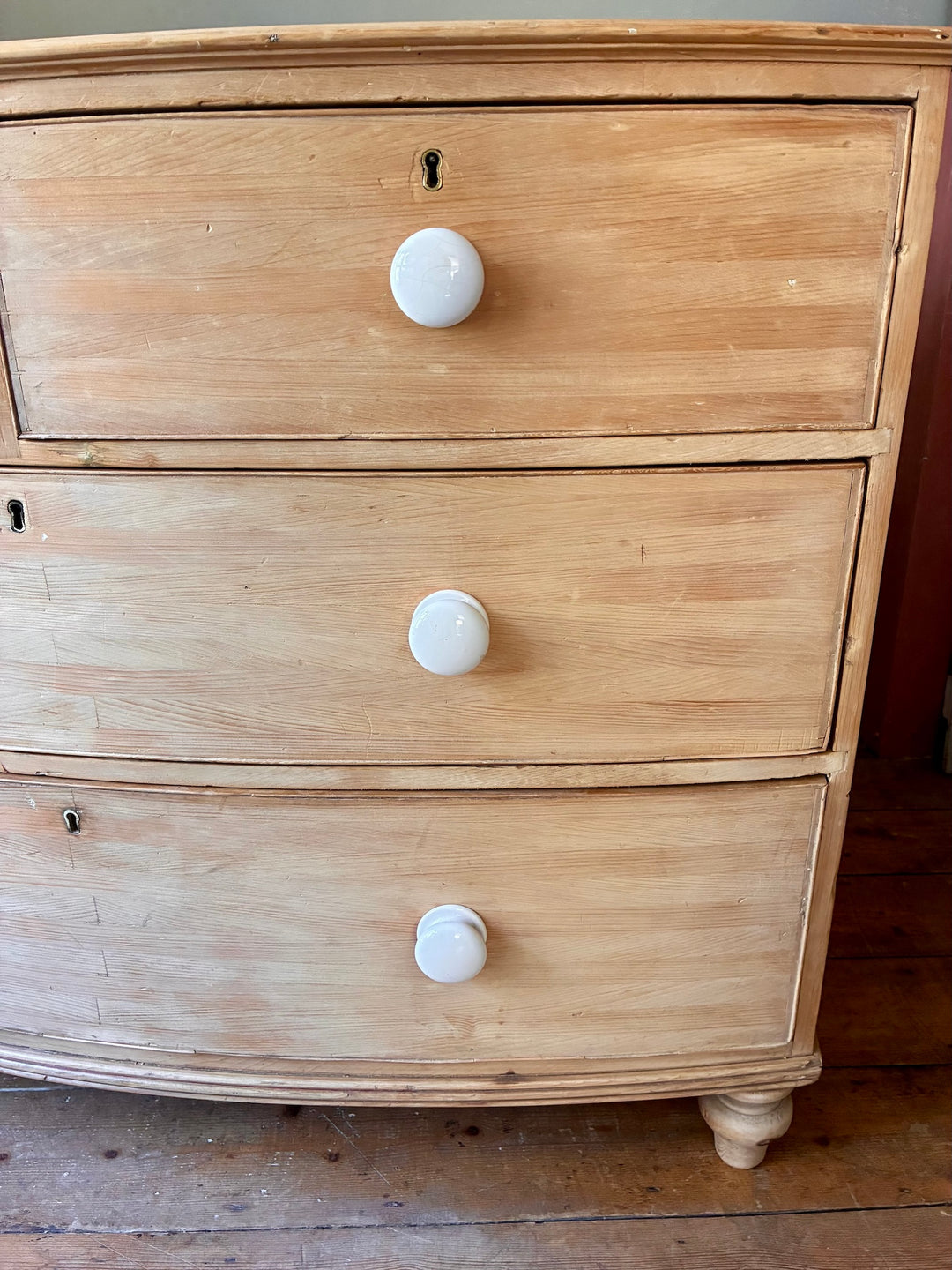 Antique Pine Bow Front Chest of Drawers showcasing white porcelain handles and rustic home charm.