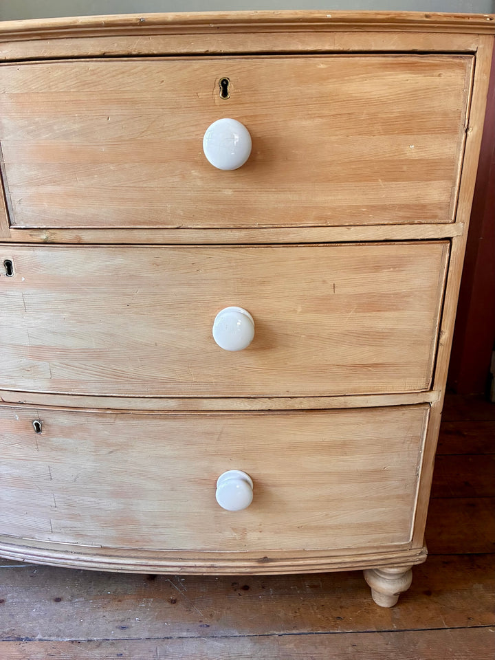 Antique Pine Bow Front Chest of Drawers showcasing white porcelain handles and rustic home charm.