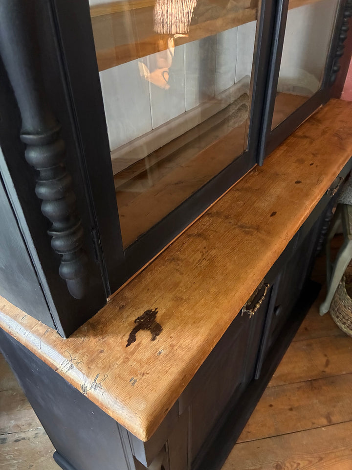 Close-up of Ebonised Victorian Pine Dresser showing the rustic wooden top and glazed doors from Source for the Goose, Devon.