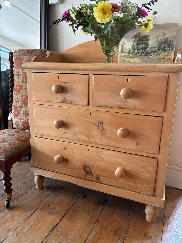 Small Antique Pine Chest of Drawers - Galleried Back with floral vase and wooden floor in a cozy interior.
