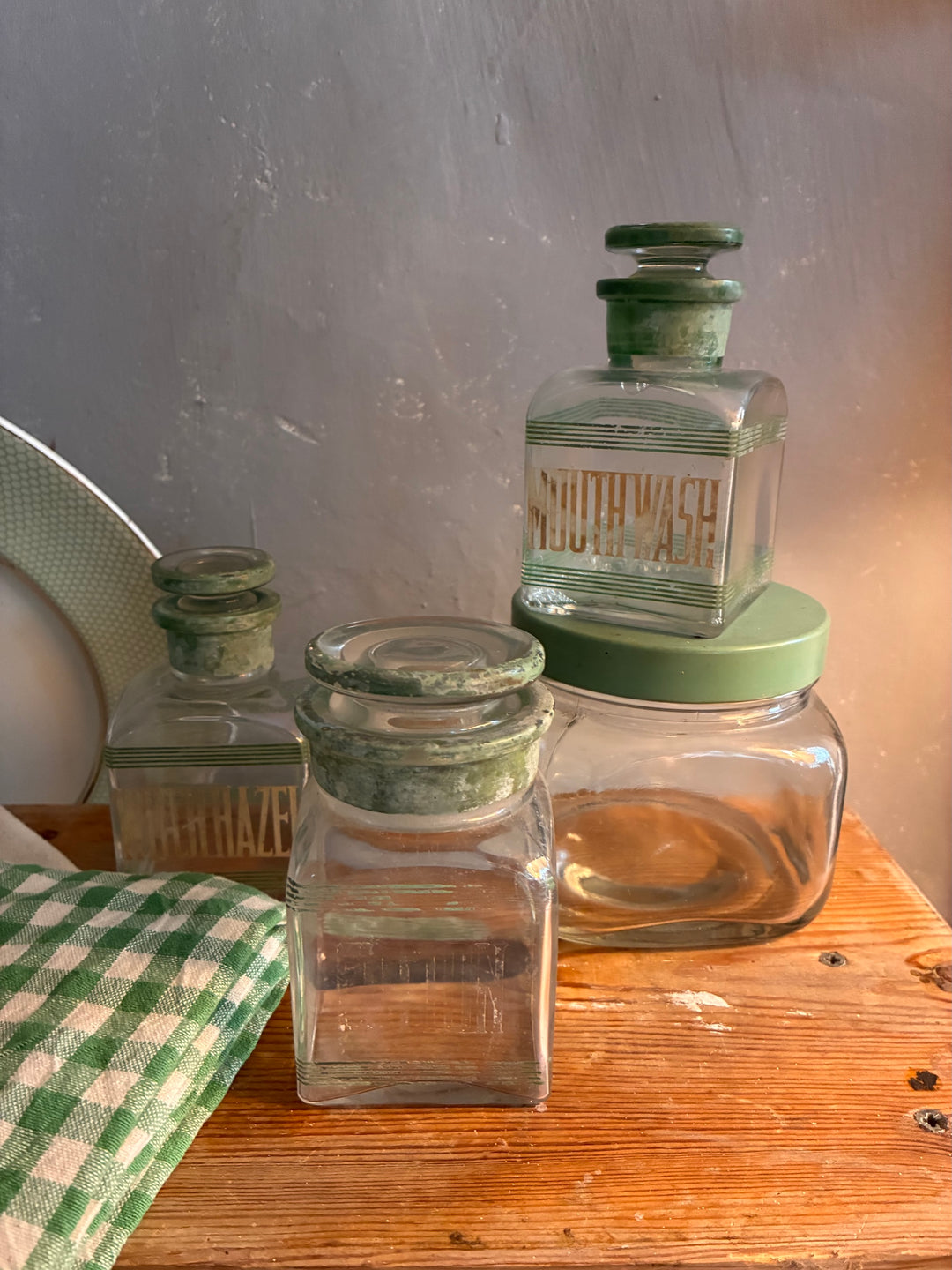 Vintage 1930s Glass Bathroom Set featuring Mouth Wash and Witch Hazel bottles with green lettering.