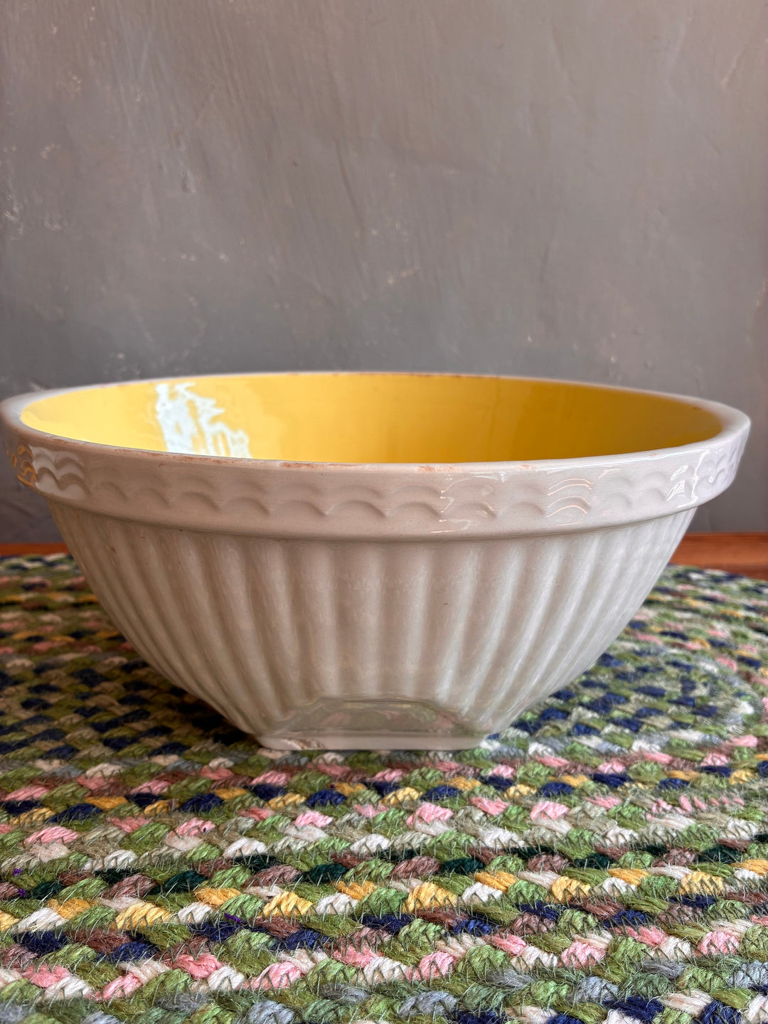 Vintage Yellow and White TG Green Easimix Bowl on a colorful mat, featuring ribbed exterior and cheerful yellow interior.