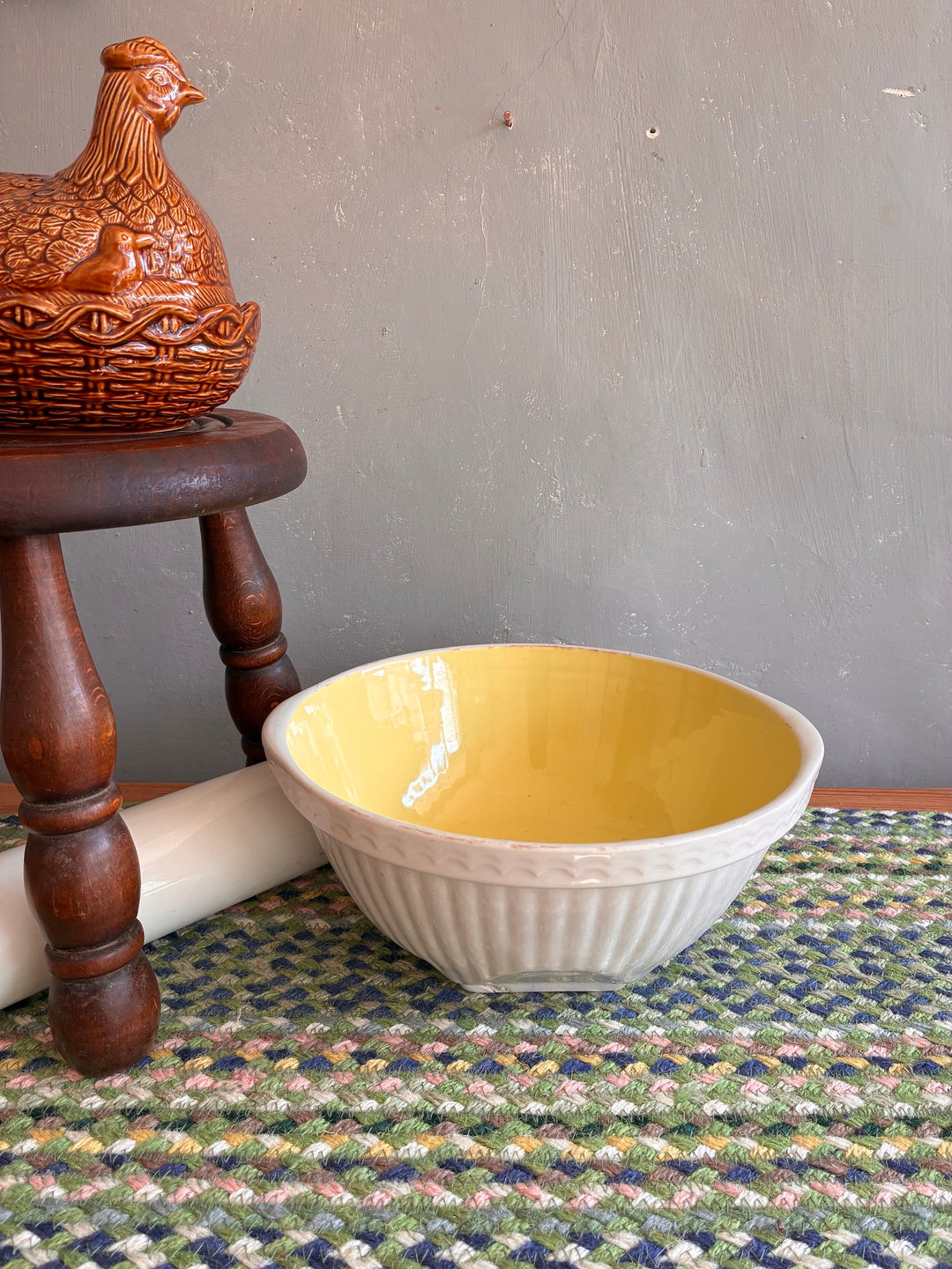 Vintage yellow and white TG Green Easimix bowl on a textured rug, showcasing retro charm and a gleaming glazed interior.