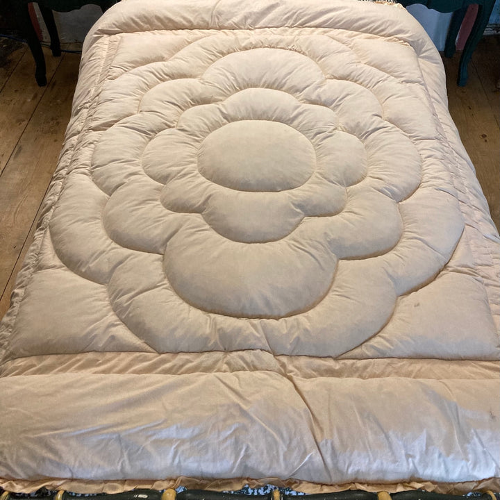 Vintage 1930s Single Eiderdown in creamy apricot gold satin on a bed.