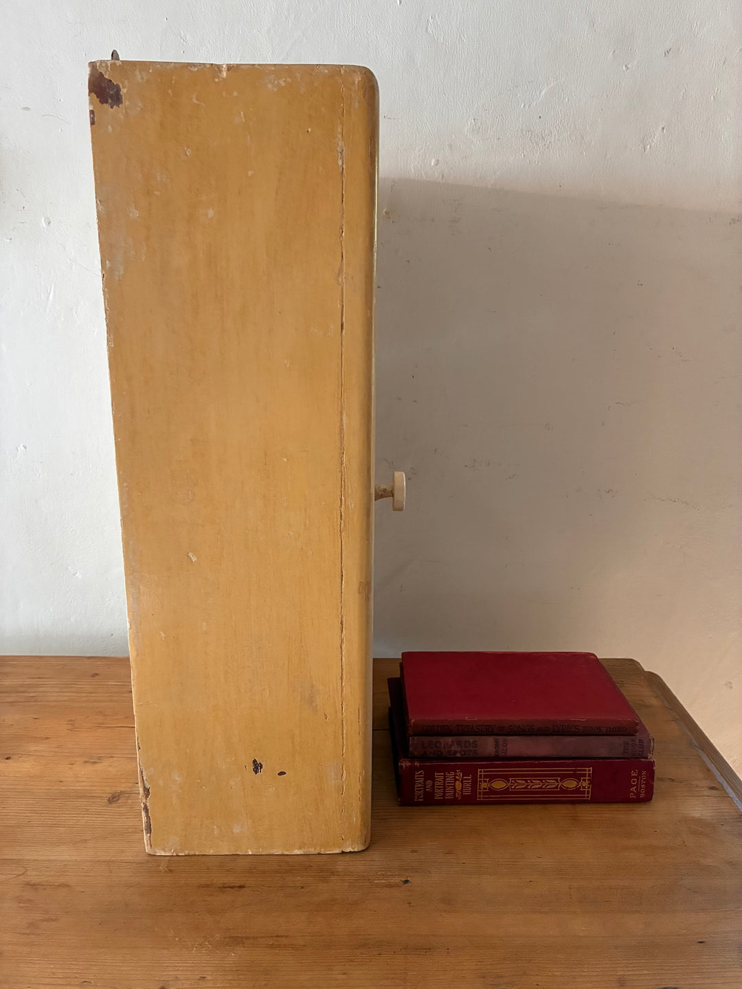 Vintage Mirrored Bathroom Cabinet displayed next to classic red books on a wooden surface.