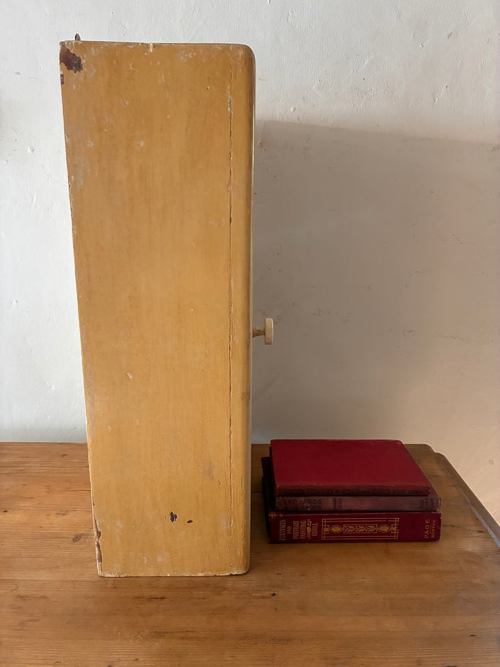 Vintage Mirrored Bathroom Cabinet displayed next to classic red books on a wooden surface.