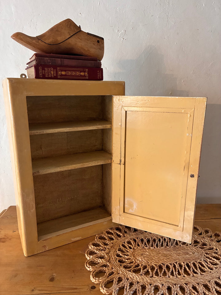 Vintage Mirrored Bathroom Cabinet displayed with wooden shoes and books on top.