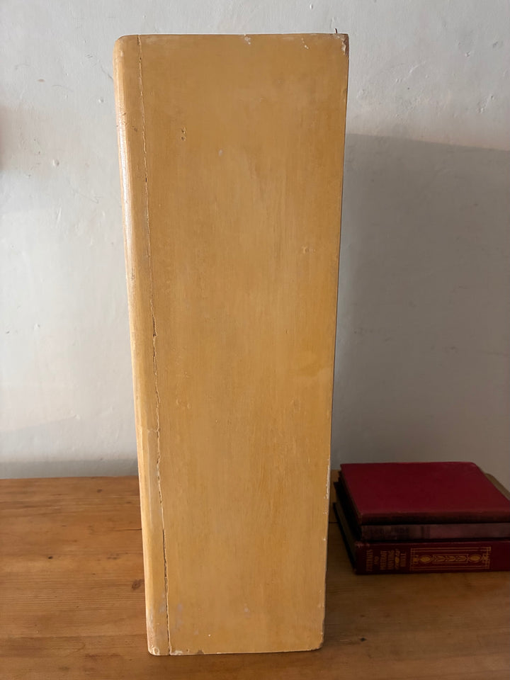 Side view of a vintage vertical cabinet showcasing a distressed yellow finish.