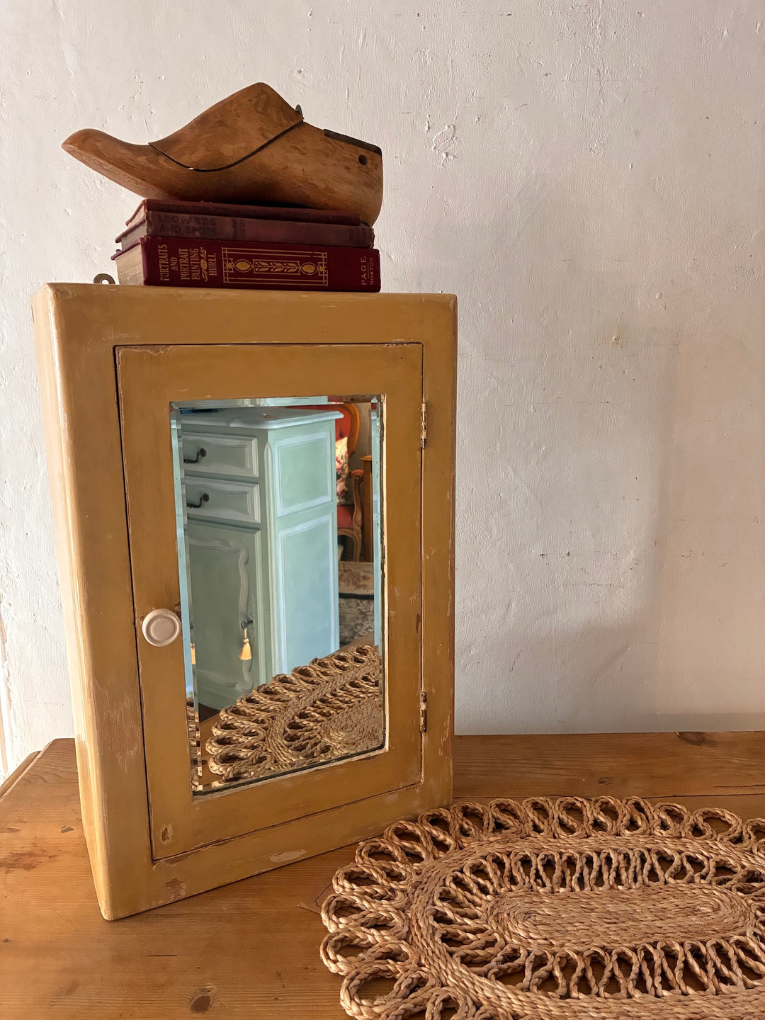 Vintage Mirrored Bathroom Cabinet styled with a wooden shoe and vintage books on a wooden table.