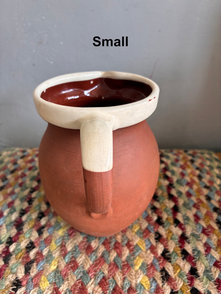 Vintage Slipware Terracotta Jug - North Devon small jug with cream slipware rim on a woven textile background.