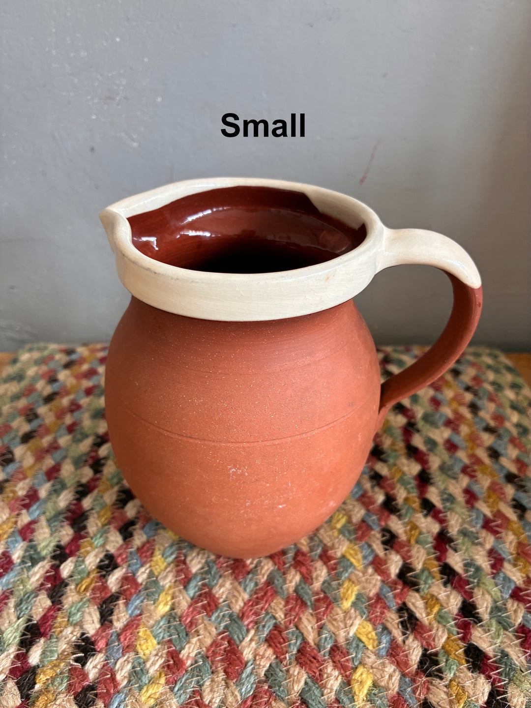 Vintage Slipware Terracotta Jug - North Devon showcased, small size with cream slipware rim on woven background.