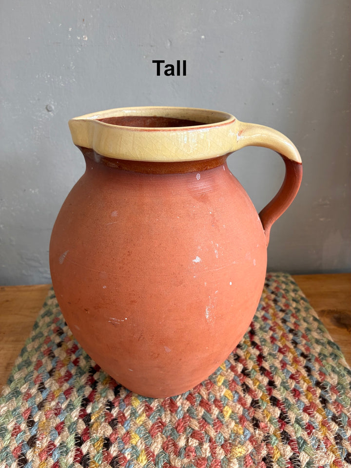 Vintage Slipware Terracotta Jug - North Devon tall terracotta jug on woven mat showcasing traditional English pottery craftsmanship.