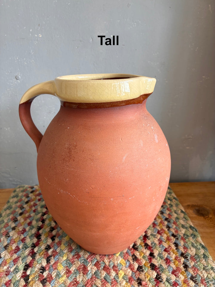 Vintage Slipware Terracotta Jug - North Devon on a woven surface, showcasing its tall design and authentic craftsmanship.