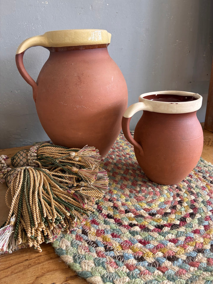 Vintage Slipware Terracotta Jug - North Devon, a pair of rustic jugs on a woven mat.