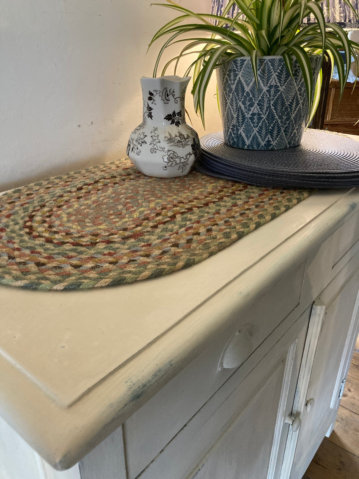 top of vintage white sideboard with braided  jute runner and plant