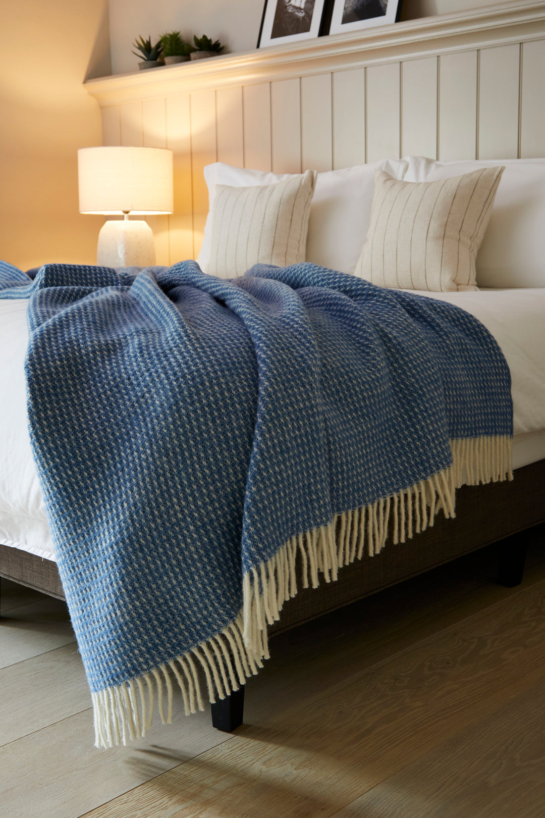 blue wool throw with cream tassels draped over bed