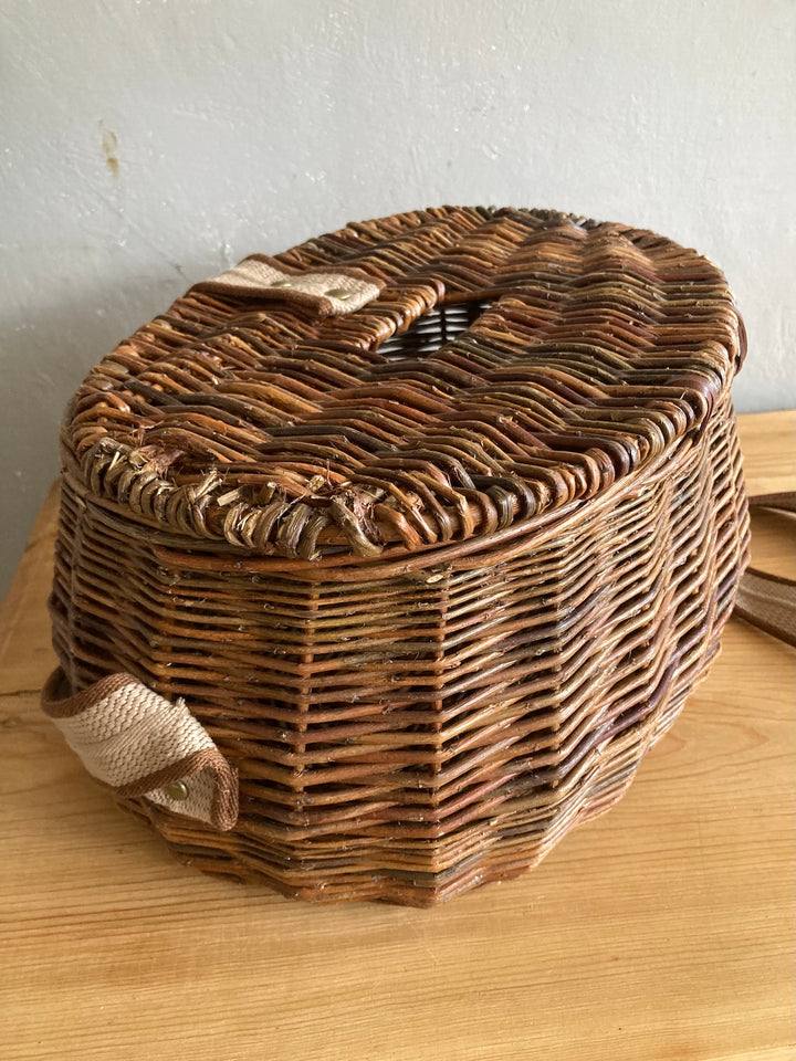 Wicker fishing creel with carrying strap, perfect for outdoor use or stylish storage in a rustic home.