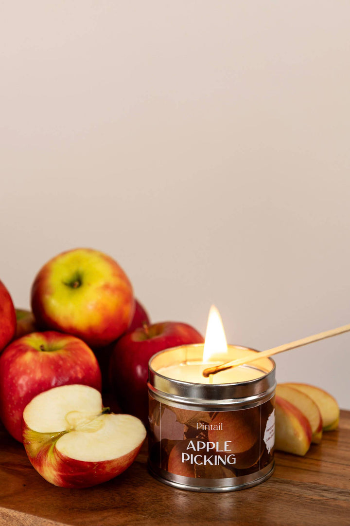 Pintail Candles Apple Picking Classic Tin Candles | Candle in a Tin surrounded by fresh apples and sliced apple.
