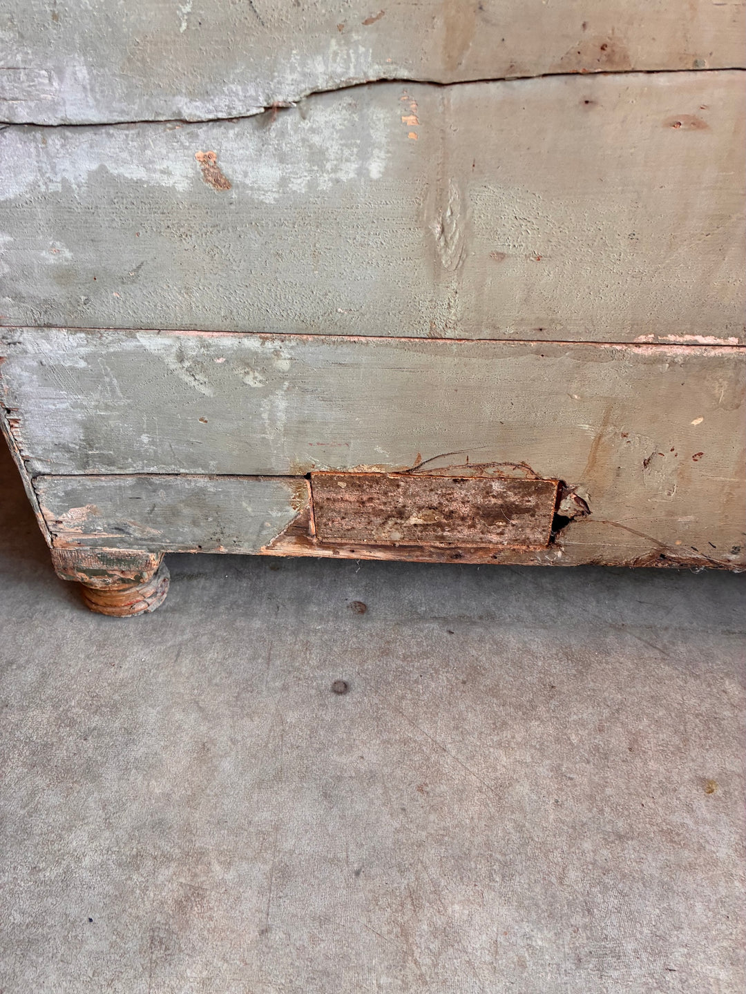 Close-up of damaged area on a small antique pine kneehole desk, showcasing its rustic character.