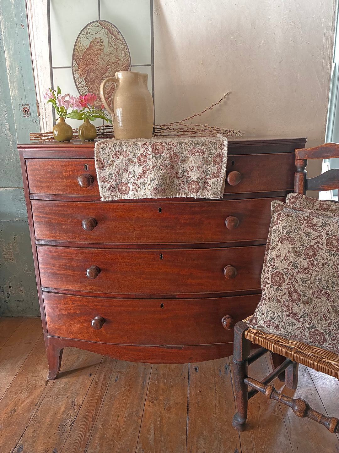 Antique Mahogany Bow Front Chest of Drawers with decorative items, vintage home decor in a rustic setting.