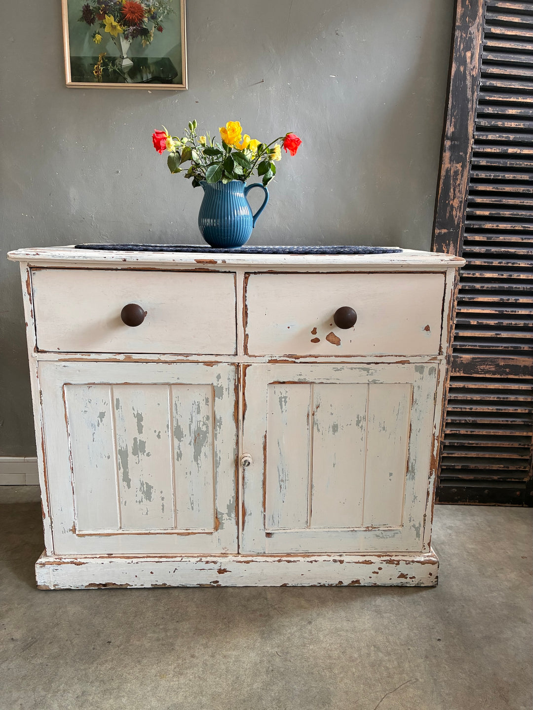 Antique Painted Pine Sideboard with chippy white paint and a bouquet of flowers on top, sourced from Source for the Goose in Devon.