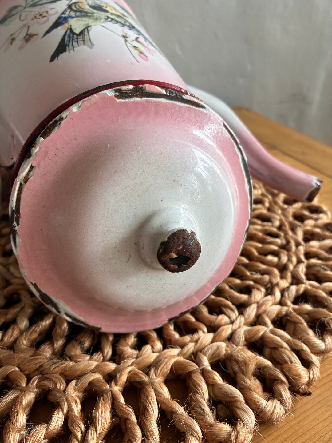 Bottom view of a vintage pink and white French enamel coffee pot with a charming distressed finish.
