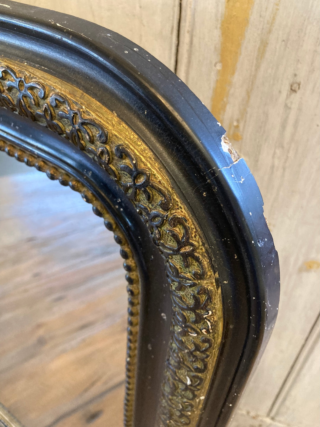 Close-up of vintage arch top French mirror's distressed black frame with gold trim, from Source for the Goose, Devon.