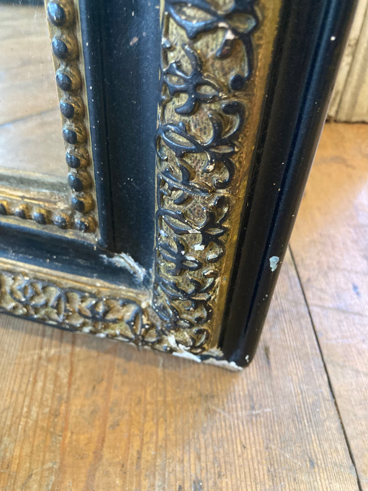 Close-up of the distressed black frame with ochre gold trim of a Vintage Arch Top French Mirror from Source for the Goose, Devon.